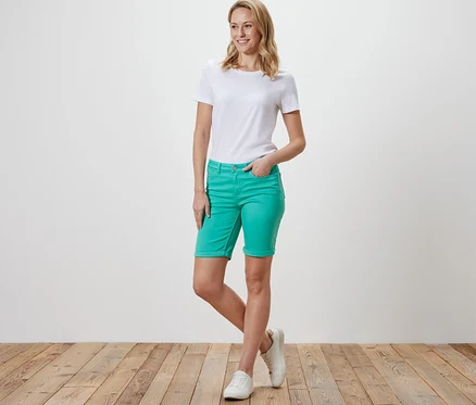 Nő pózol vízkék Denim rövidnadrágban ‒ »Lea« fazonban és fehér pólóban.