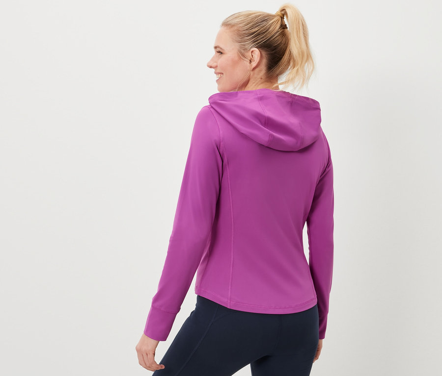 Nő sportdzsekit és sötétkék leggingset visel.