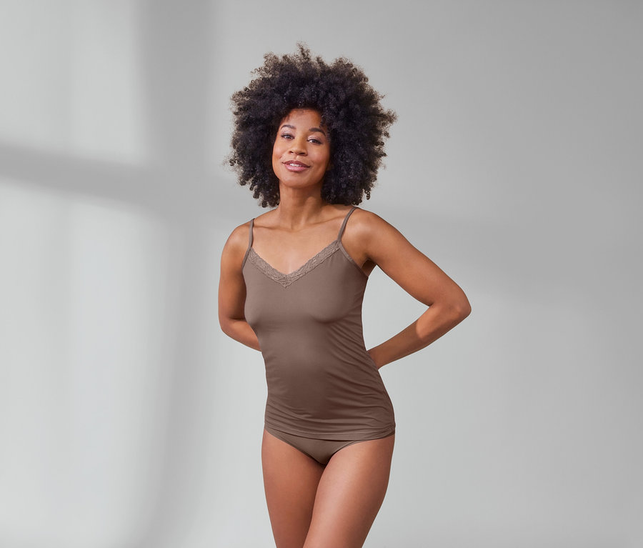 Afro-amerikai nő pózol mogyoró színű női trikóban és 5 darab bézs Magic Cut alsóban.