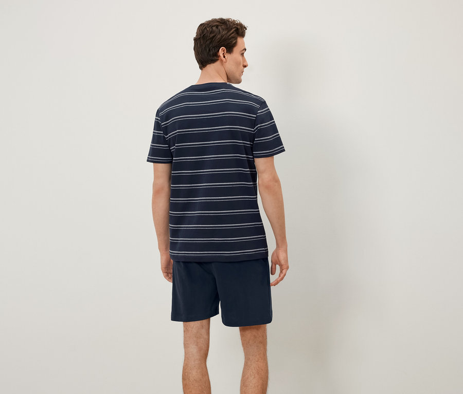 Hátulról látható férfi csíkos pólót és rövidnadrágot visel.