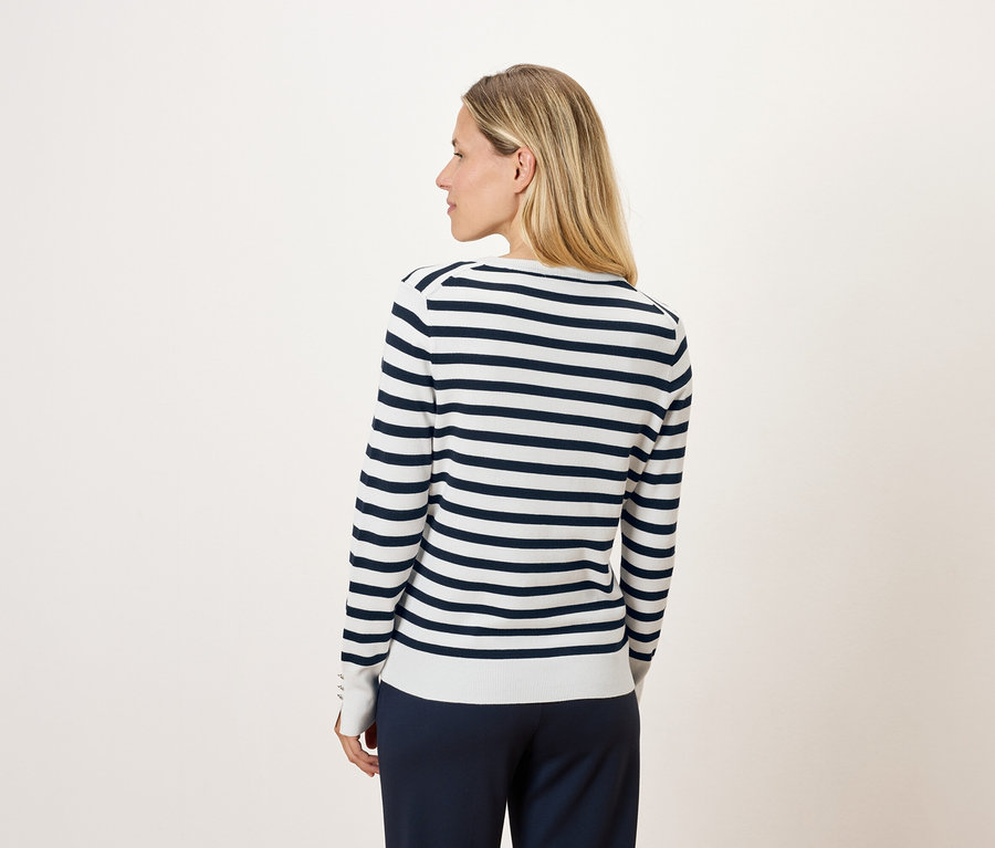 Hátulról egy szőke nő, csíkos, hosszú ujjú pulóverben.