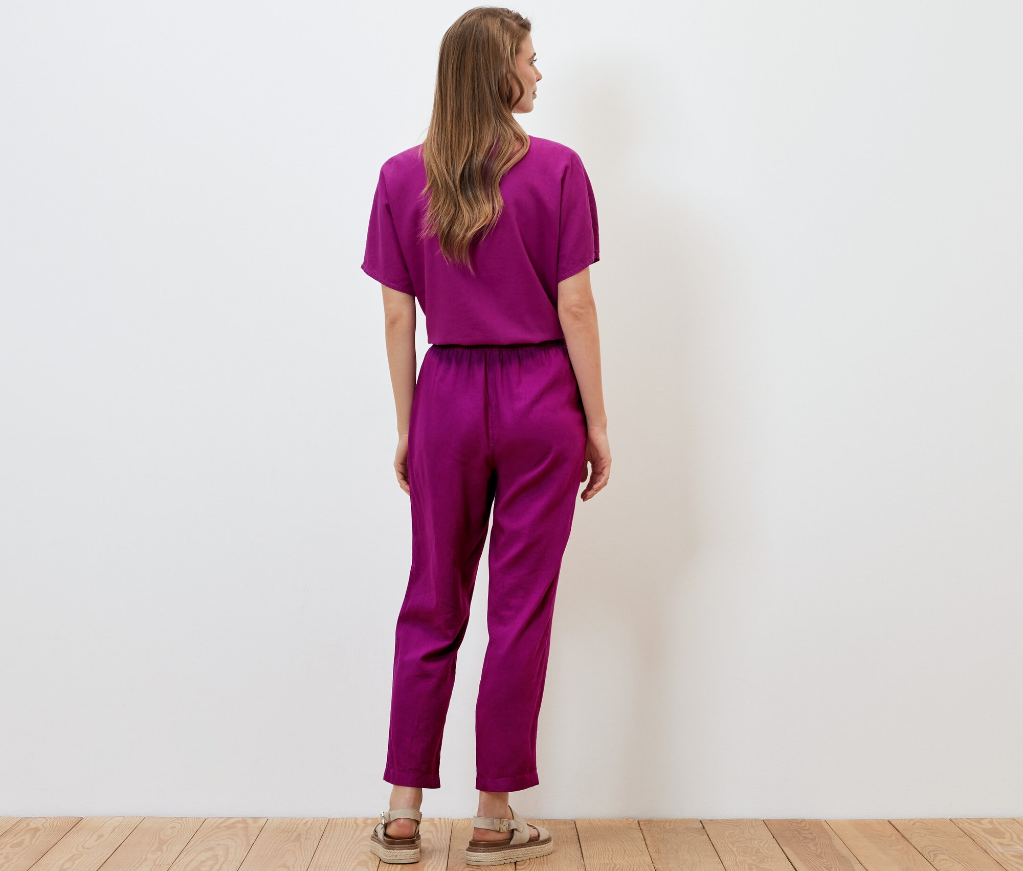 Hátulról látható nő visel fukszia színű, lenvászon női lezser nadrágot.