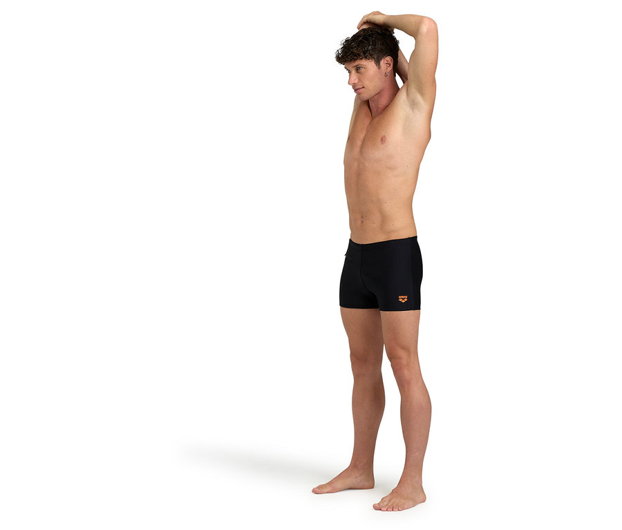 Férfi nyújtózkodik, fekete fürdőnadrágot visel.