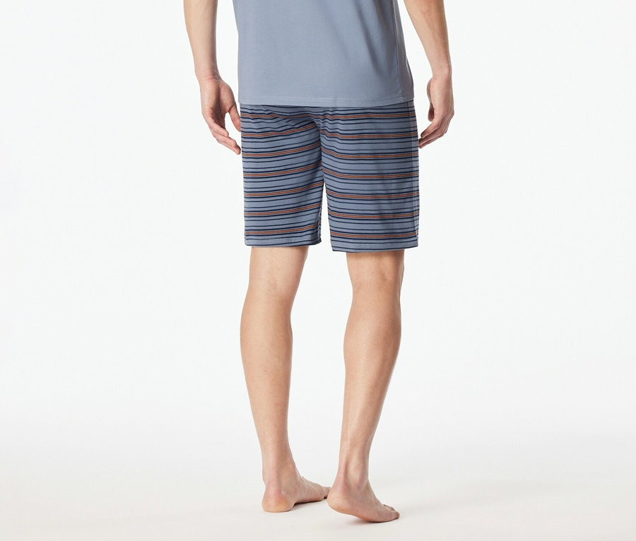 Hátulnézet egy kék pólót és csíkos rövidnadrágot viselő férfiról fehér háttér előtt.