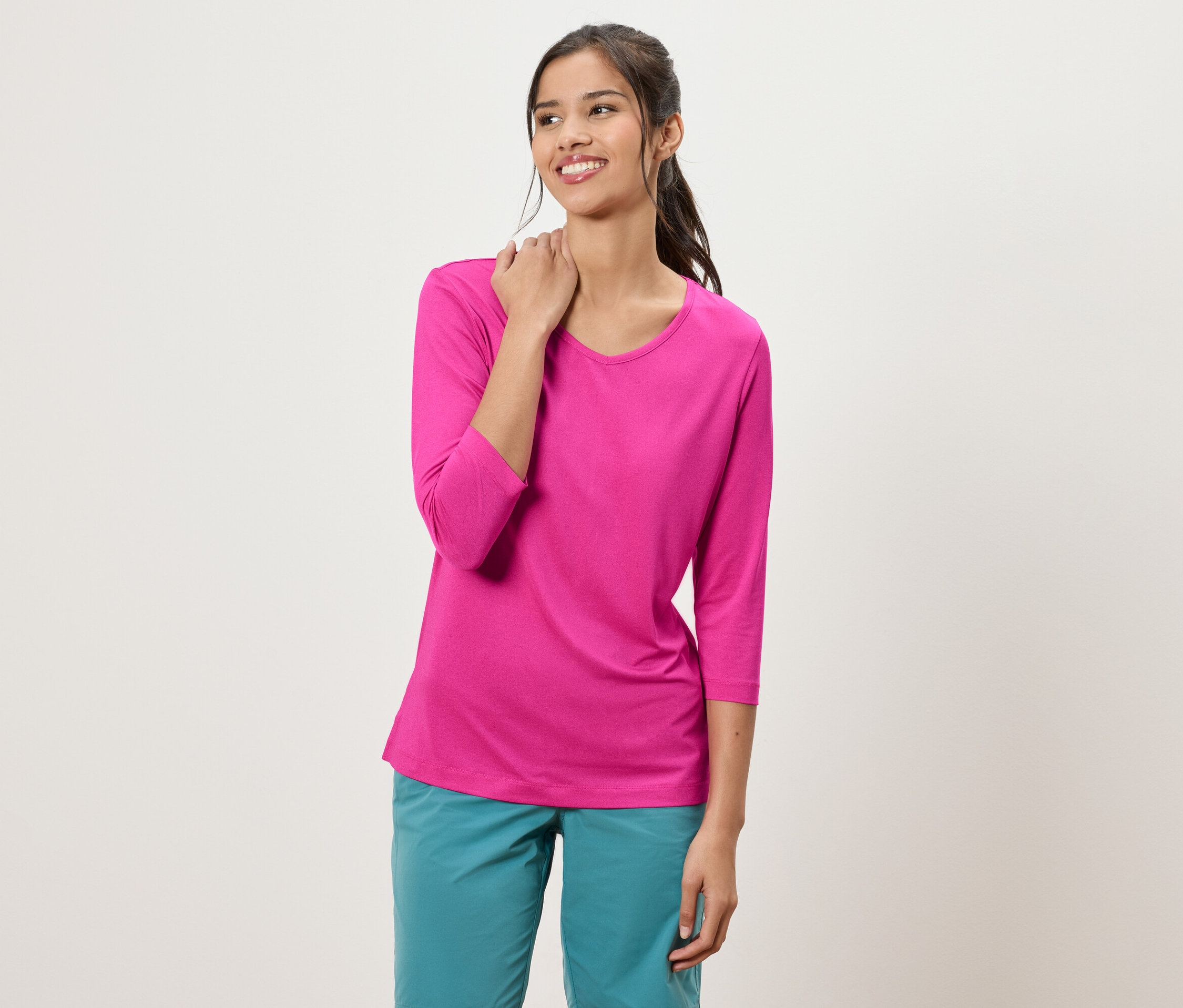 Lófarkas nő rózsaszín, háromnegyedes ujjú felsőt és türkizkék nadrágot visel.