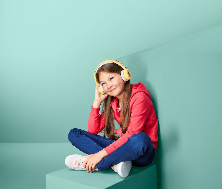 Egy lány ül és zenét hallgat a Gyerek fejhallgató, Bluetooth segítségével.