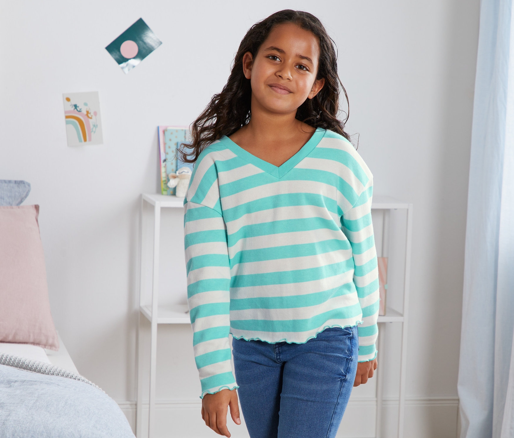 Egy lány kék csíkos bio pamut szabadidőfelsőben pózol.