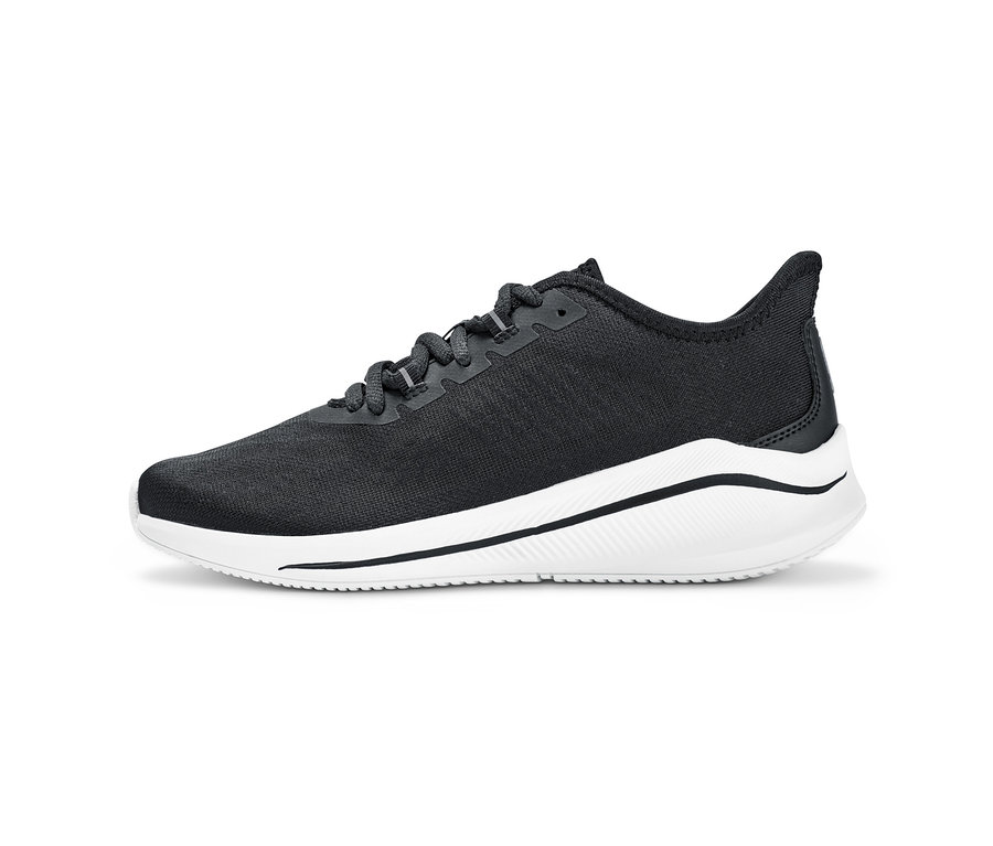 Egy fekete felsőrésszel és fehér talppal rendelkező női sneaker cipő részletfotója.