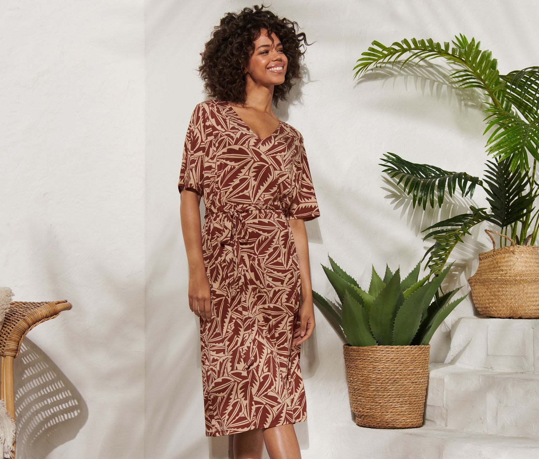 Nő pózol egy nyomtatott jersey ruhában.