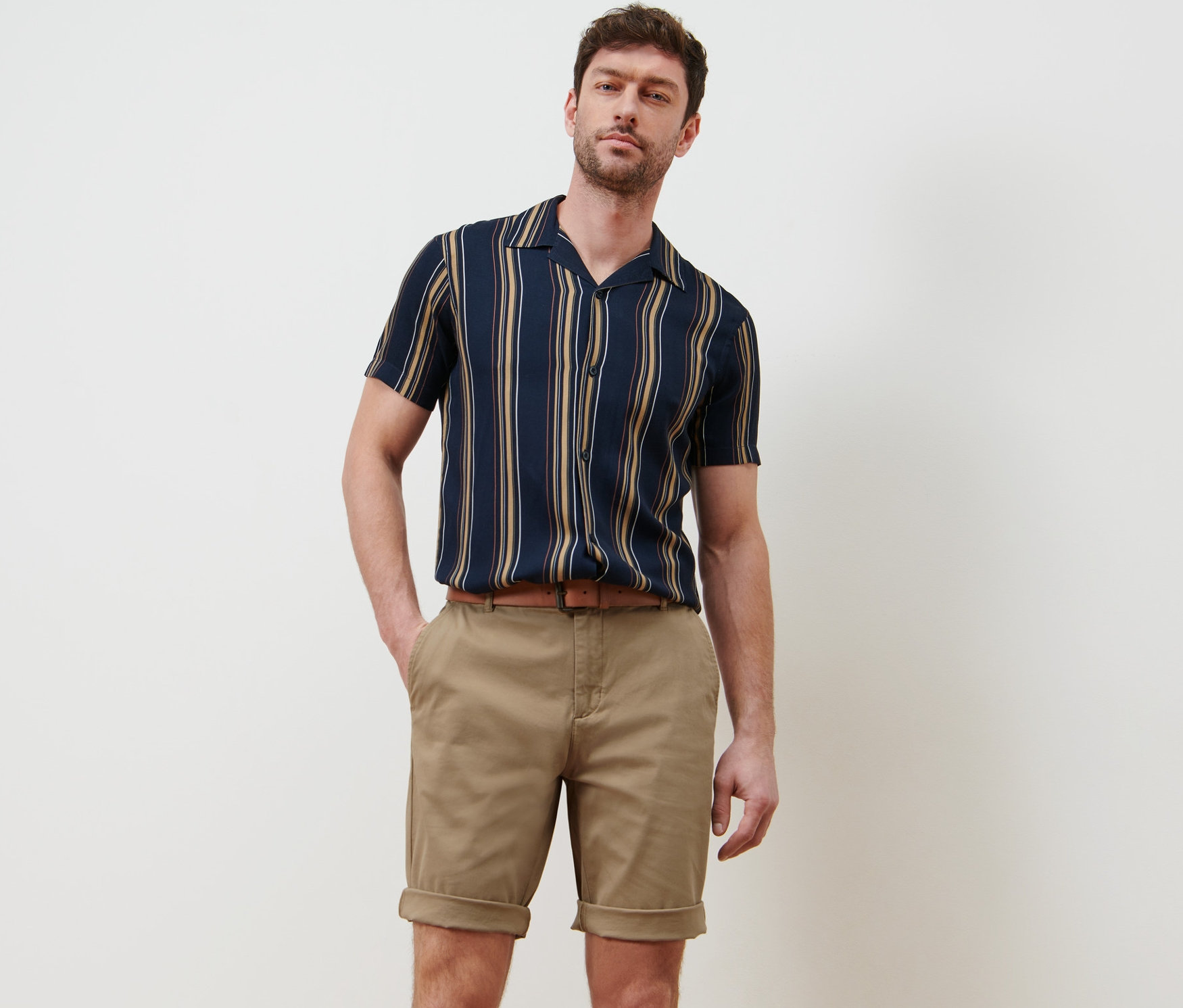 Férfi pózol bézs színű chino rövidnadrágban.