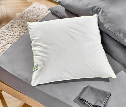 Az ágyon két irisette® greenline tollpárna fekszik, egy kb. 90 x 70 cm-es és egy kb. 80 x 80 cm-es.