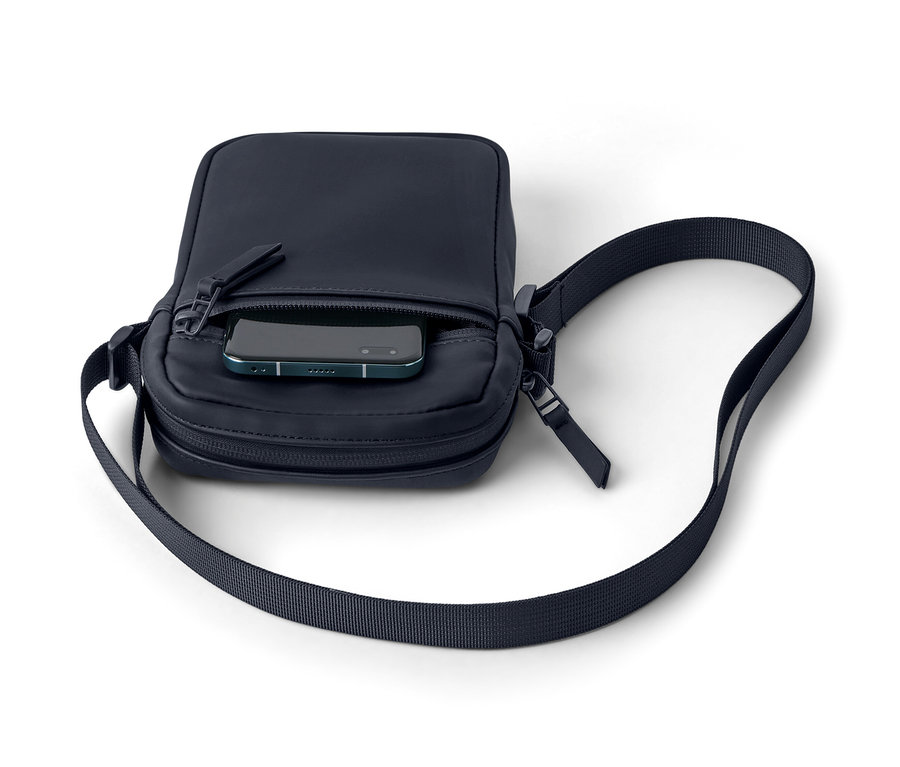 Egy sötétkék, vízhatlan oldaltáska, telefonnal a zsebében.