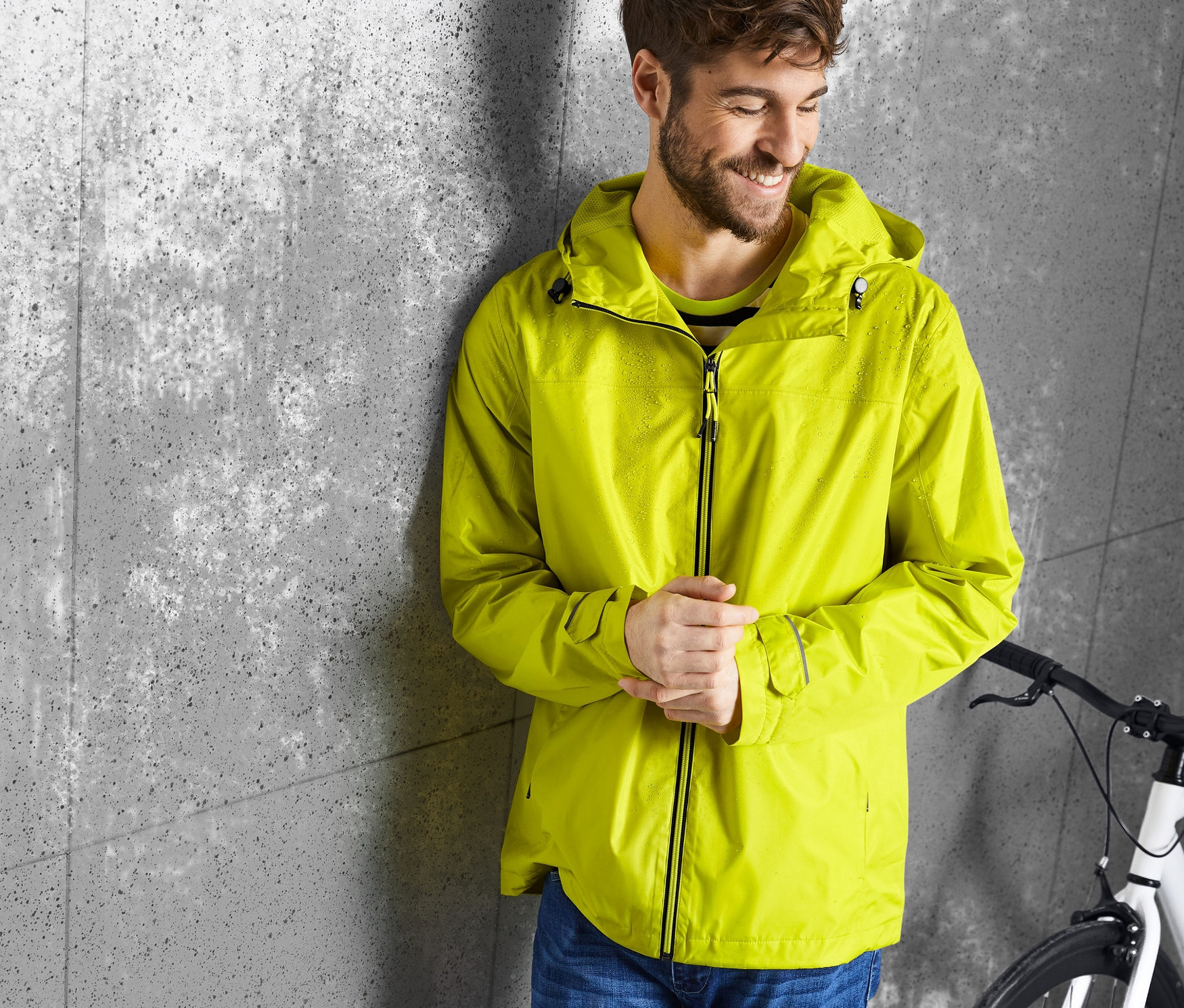 Férfi a falnak dőlve sárga esőkabátot visel.