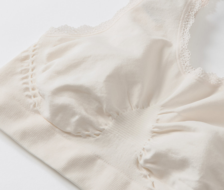 Egy krémszínű, varrás nélküli, csipkés bustier részlete.