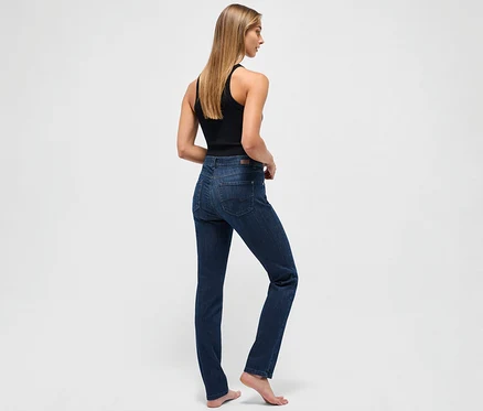 Egy nő háttal áll a kamerának, sötétkék Angels »Cici« slim fit farmert és fekete trikót visel.