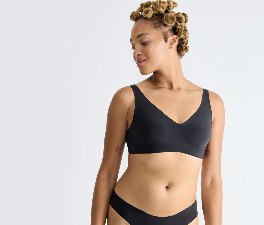 Nő visel fekete sloggi ZERO Feel 2.0 puha melltartót.