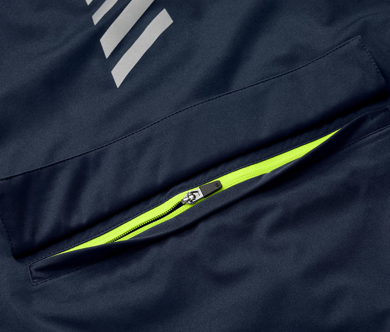 Egy kék Rad-Regenjacke kerékpáros esőkabát részlete neonzöld cipzárral a zseben és fényvisszaverő elemekkel.