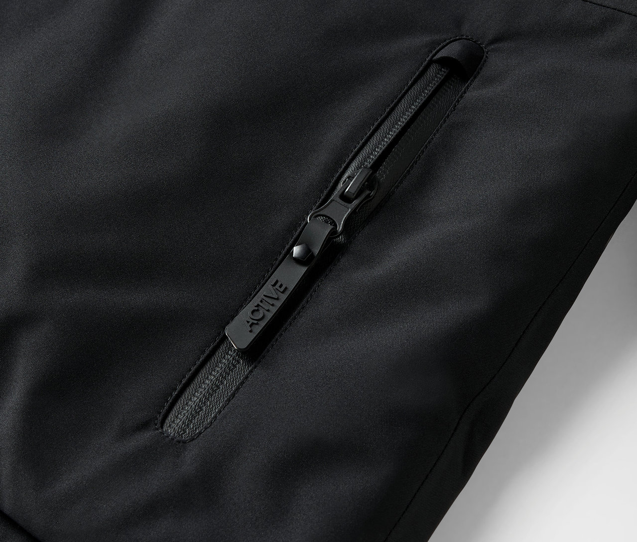 Egy fekete cipzár részlete egy kabáton, ACTIVE felirattal.
