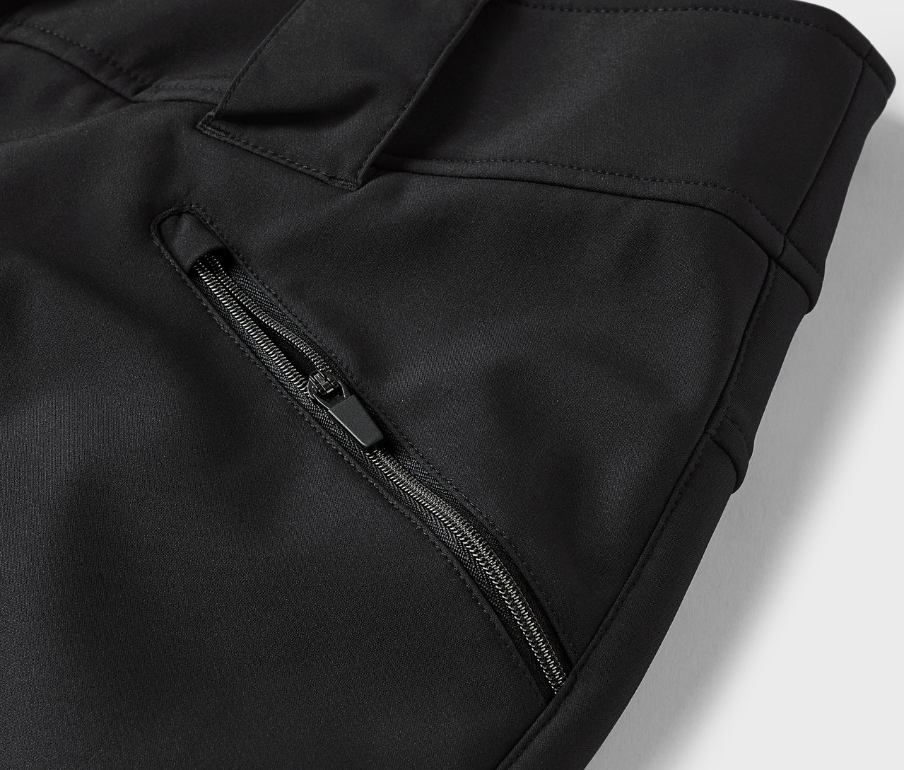 Egy fekete nadrág részlete cipzáras zsebbel.