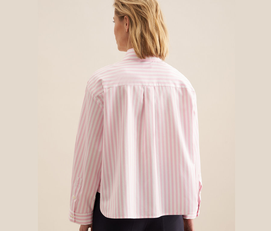 Nő visel rózsaszín, fehér csíkos Seidensticker oversize ingblúzt.