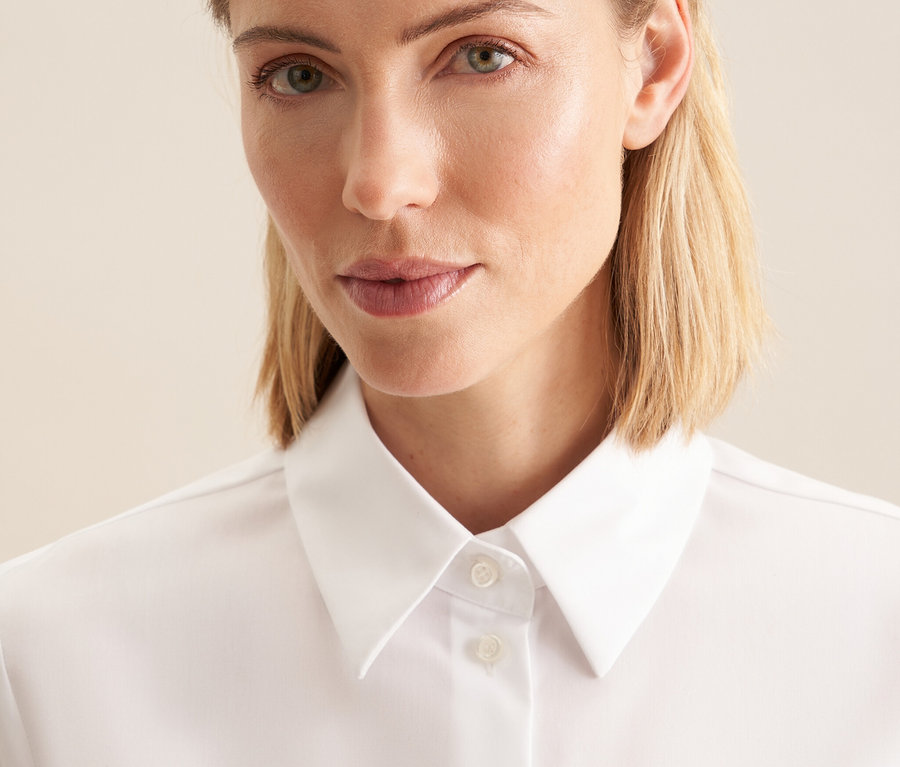 Egy nő portréja fehér, vasalásmentes Seidensticker blúzban.