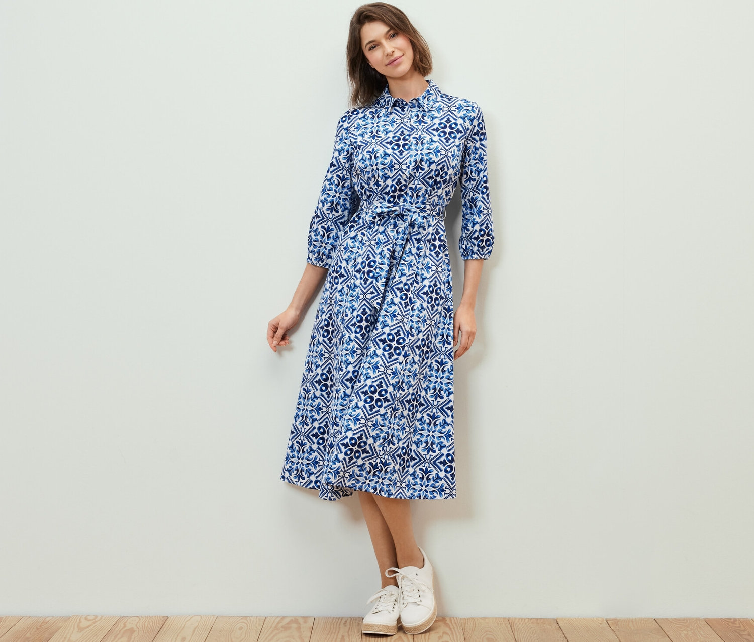 Nő pózol egy mintás midi ruhában.