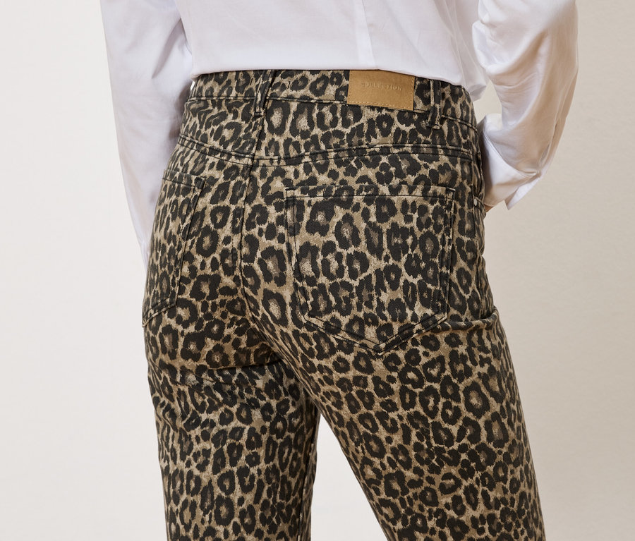 Hátulnézet egy leopárdmintás nadrágot és fehér inget viselő személyről.