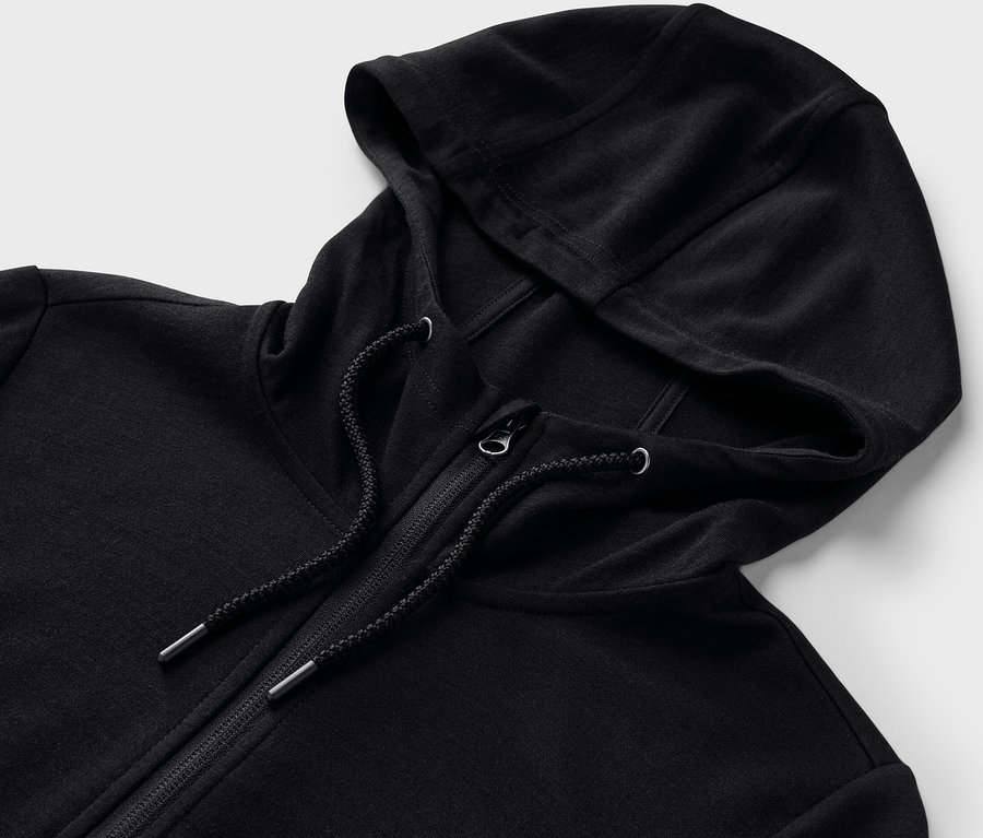 Egy fekete, RWS minősített gyapjú kapucnis felső részletének közeli képe, cipzárral.