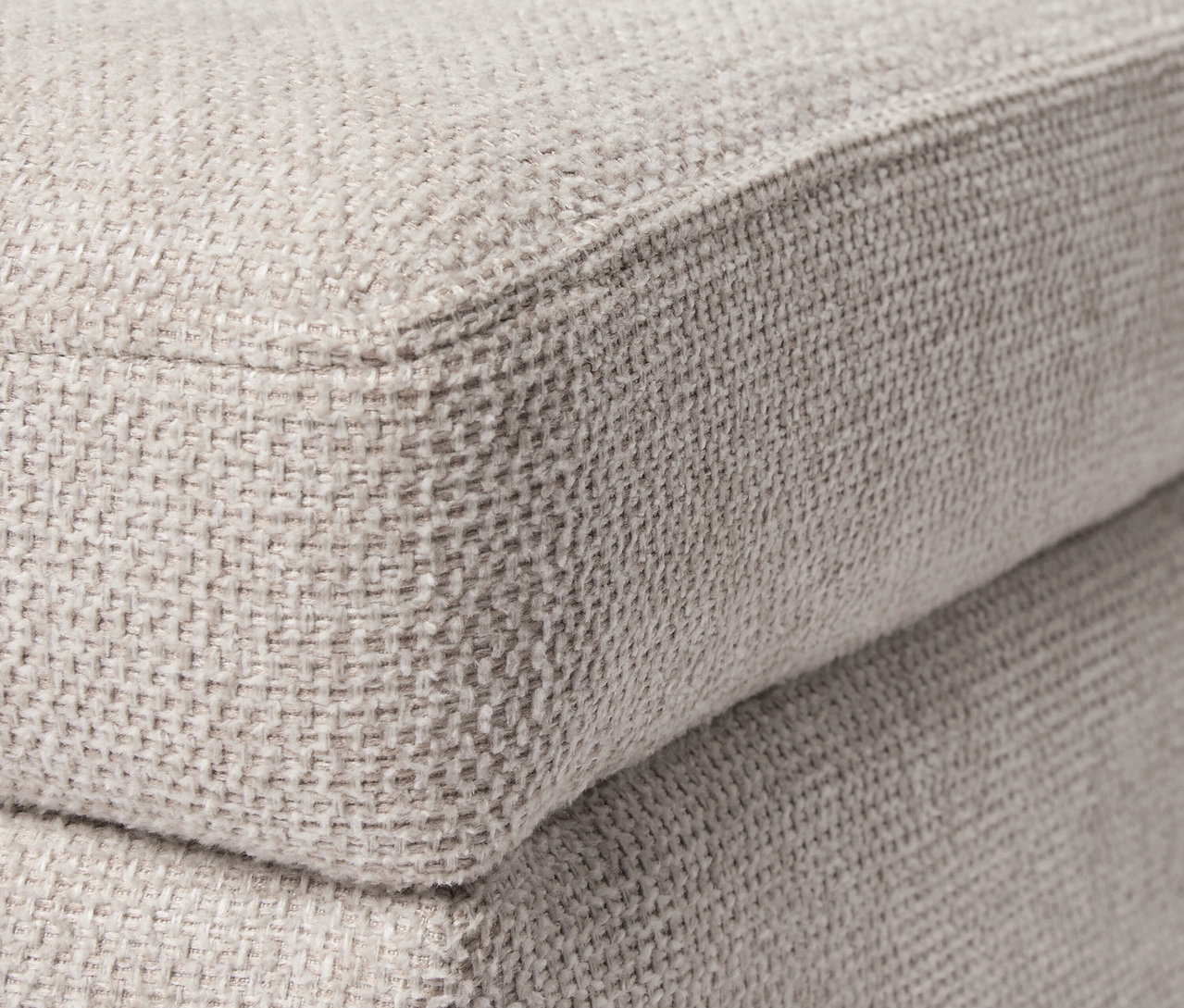 Közeli kép egy bézs puffról.