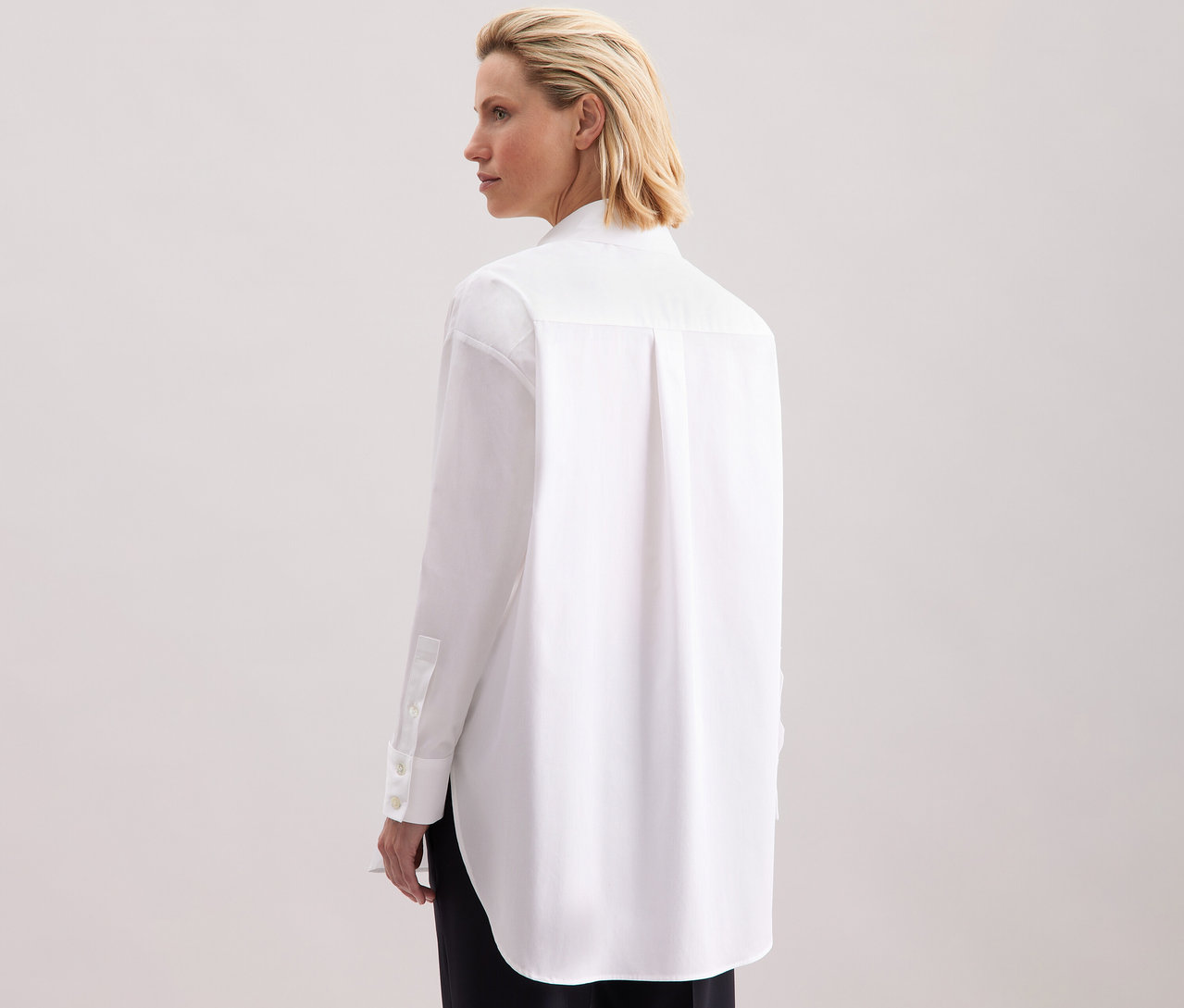 Hátulról látható nő fehér Seidensticker túlméretes hosszú ingblúzban.