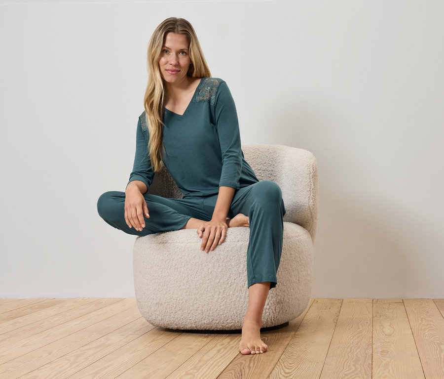 Nő ül egy szőrös széken zöld pizsamában.