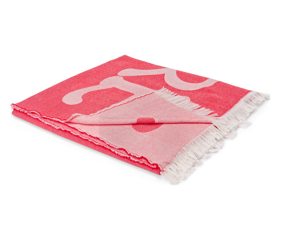 Összehajtott, piros takaró, fehér mintával és rojtokkal a végein.