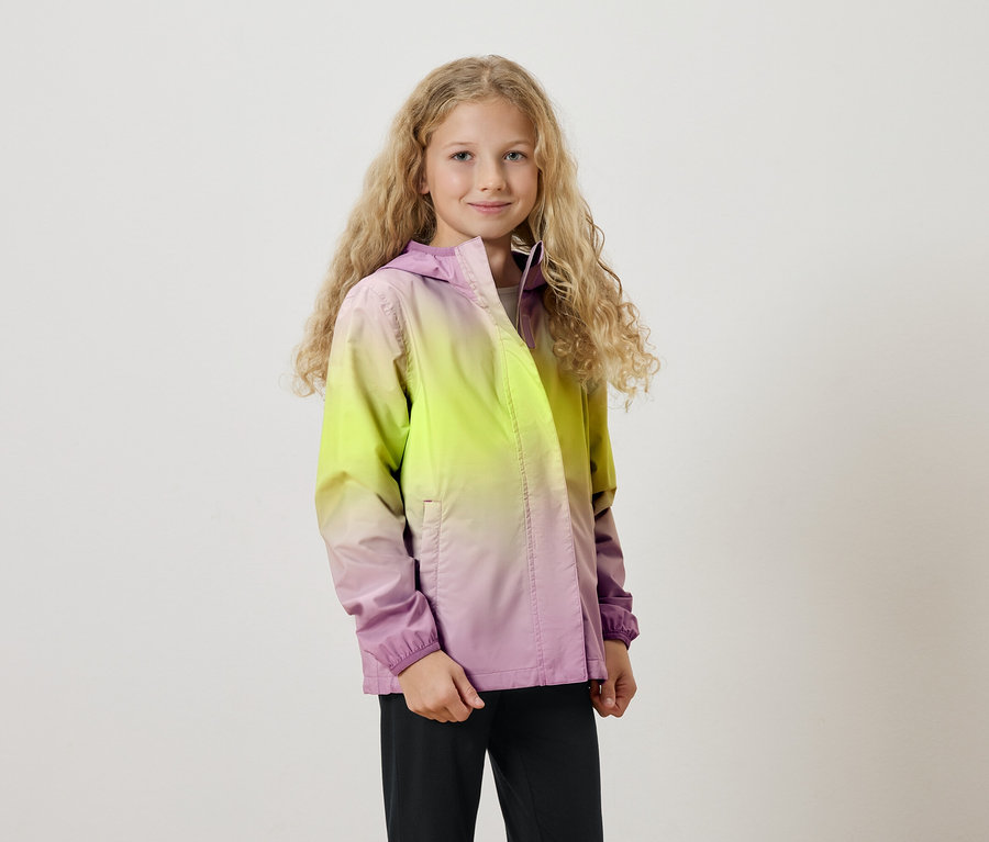 Egy hosszú, szőke, göndör hajú lány sárgából lilába átmenetes színű kapucnis kabátot visel.