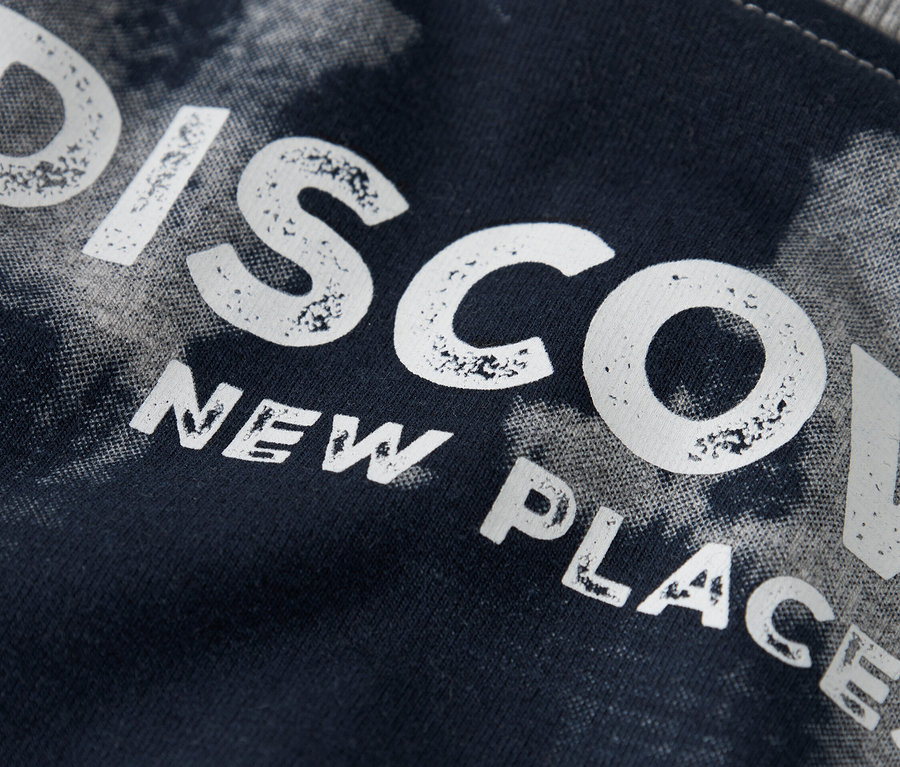 Egy sötétkék szövet közeli képe, melyre a "DISCOVER NEW PLACES" felirat van nyomtatva.