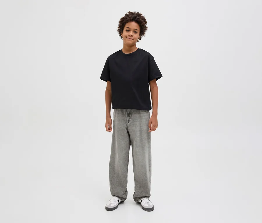 Egy fiú fekete pólót és szürke Jack&Jones JJOrginial Alex farmernadrágot visel.