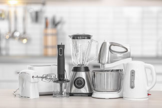 Mindenféle konyhai eszköz: Különféle konyhai háztartási cikkek, mint például egy mixer, egy keverő, és egy vízforraló is a konyhapulton van.