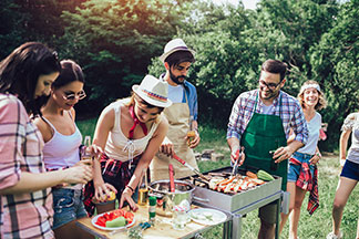 Zöldségeket is lehet a grillen készíteni: fiatalok grilleznek és zöldségeket előkészítenek egy kis asztalon.