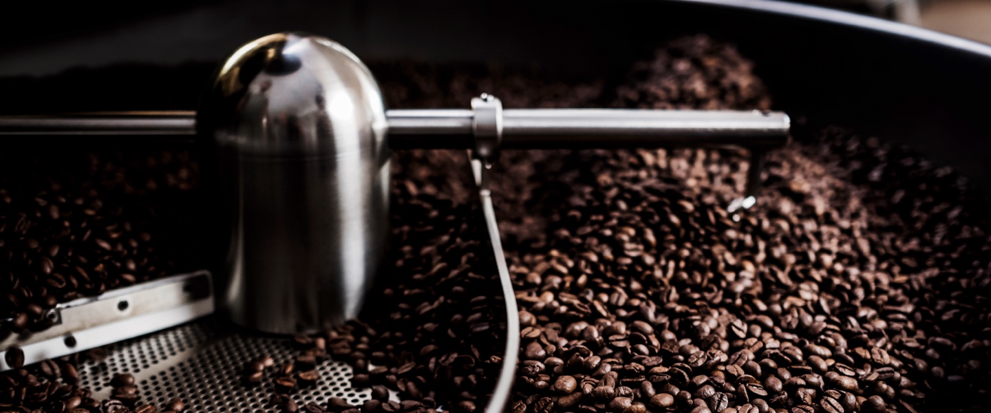 Stimmungsvolles Bild zwischen Mann und Kind, wobei das Kind gemahlenen Kaffee in einen Filter schüttet.