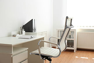 Egy modern, ergonomikus, fehér ülőfelületű szék egy fehér íróasztal mellett van.