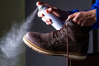 Közelkép egy férfi bőrcsizmáról, amelyet spray-vel impregnálnak.