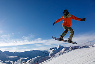 Sportdzsekik a télre: Egy snowboardos a havas hegyekben ugrat.
